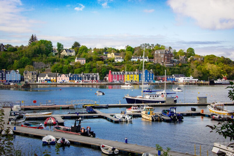 Colorful harbor-side town on Scottish island, with dock with small boats in foreground