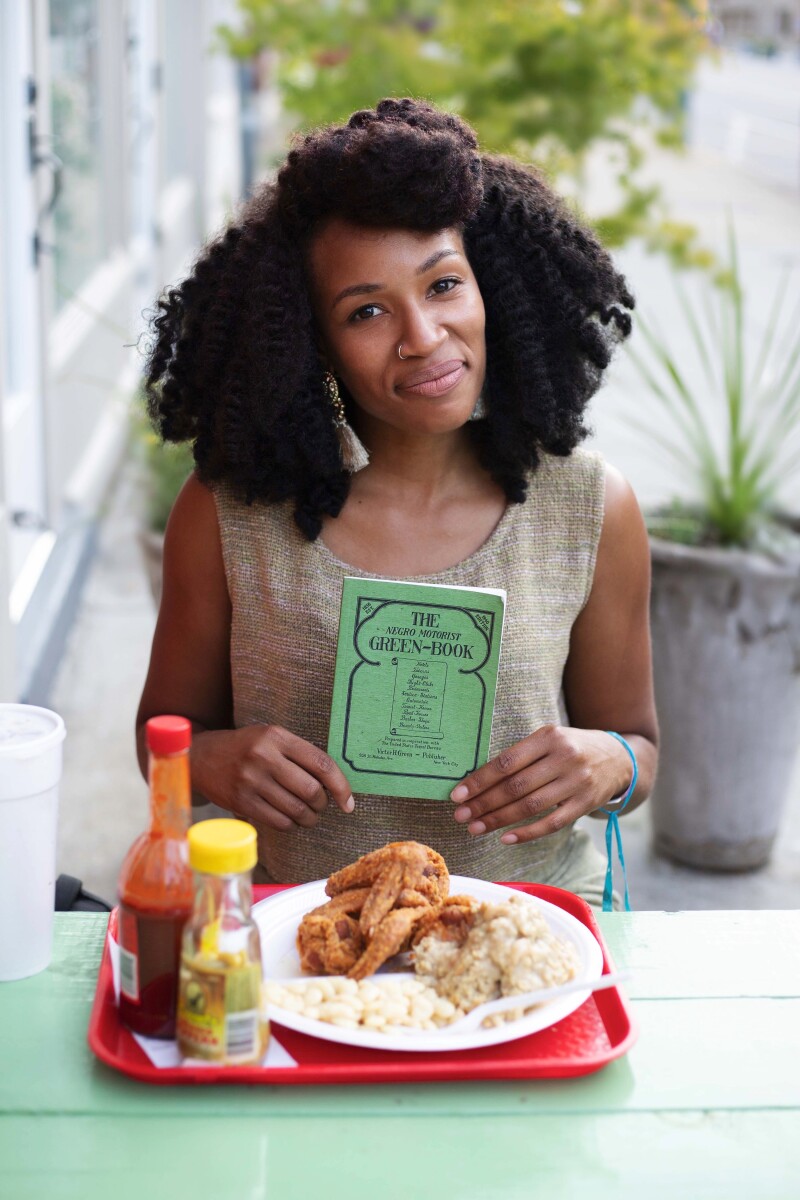 Author Martinique Lewis, aka @martysandiego, holding up a copy of Victor Hugo Green’s original “Green Book.”