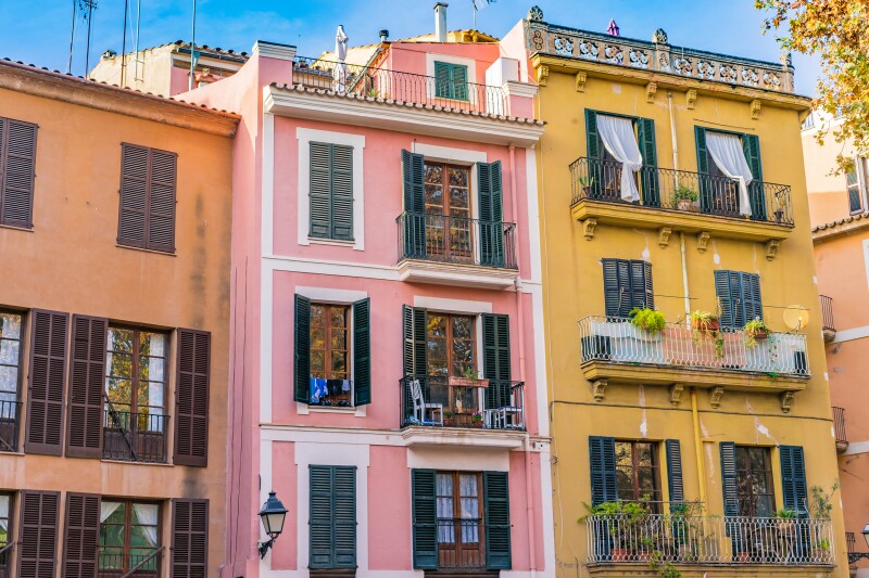 A row of three townhouses in Mallorca: orange, pink, and yellow