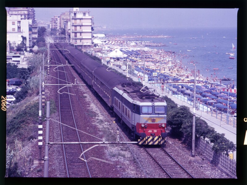 An '80s-era train in Italy with the beach and many beach umbrellas at right