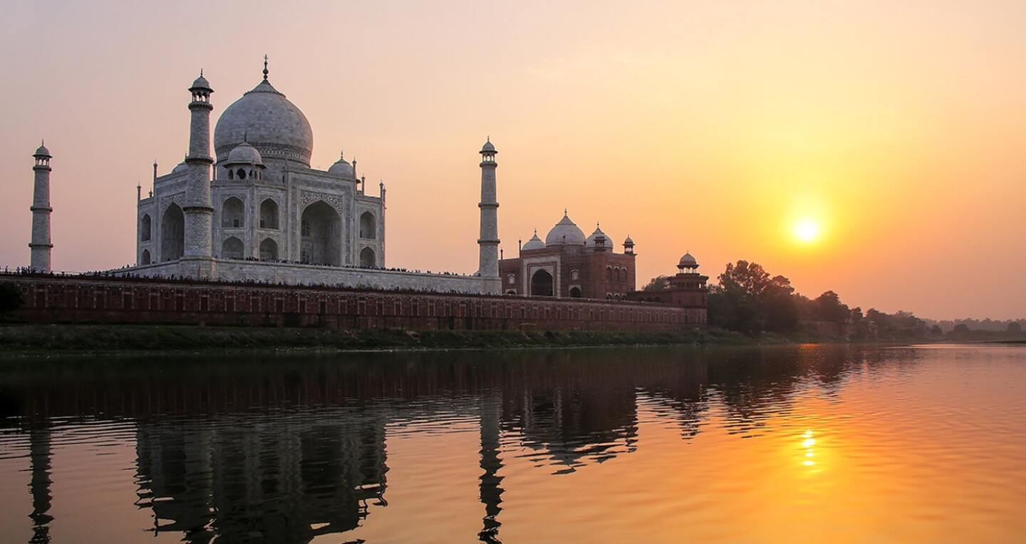 The sun shine through a hazy sky and casts a warm glow over the Taj Mahal