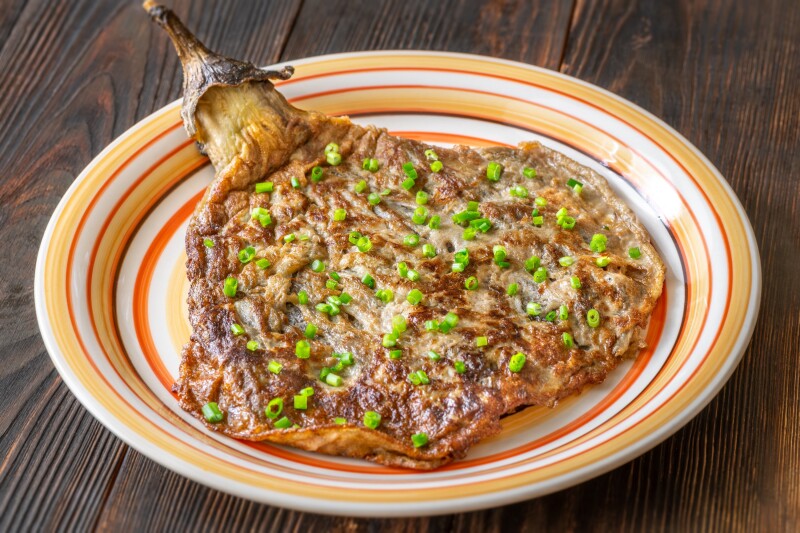 Filipino eggplant omelette topped with chopped scallions on a plate