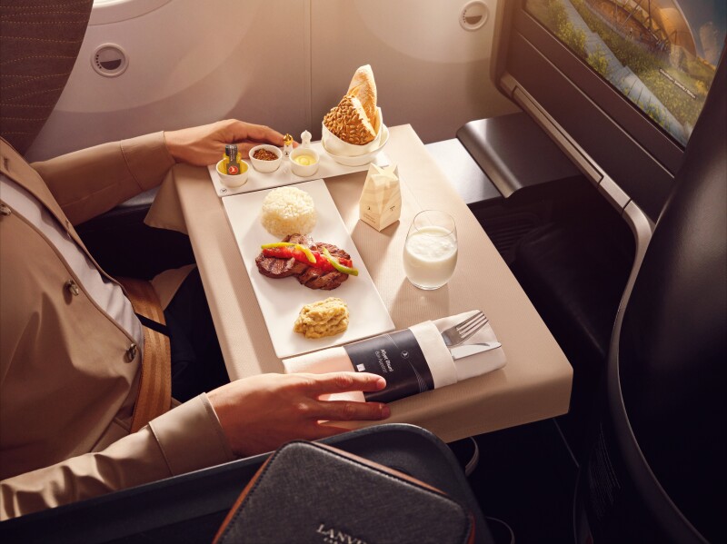 Close-up of a meal served in business class on Turkish Airlines featuring grilled meat, rice, a purée, and bread on the side