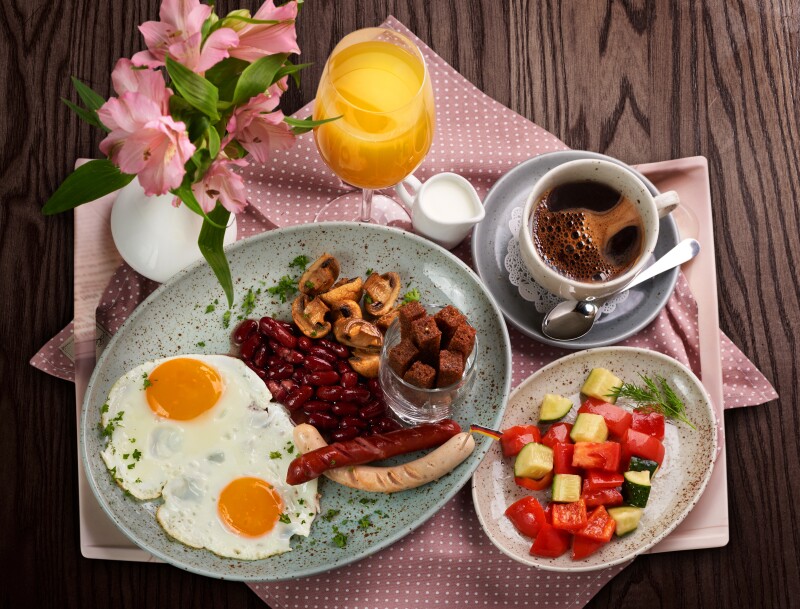 A traditional german breakfast with vegetables, eggs, and sausages.
