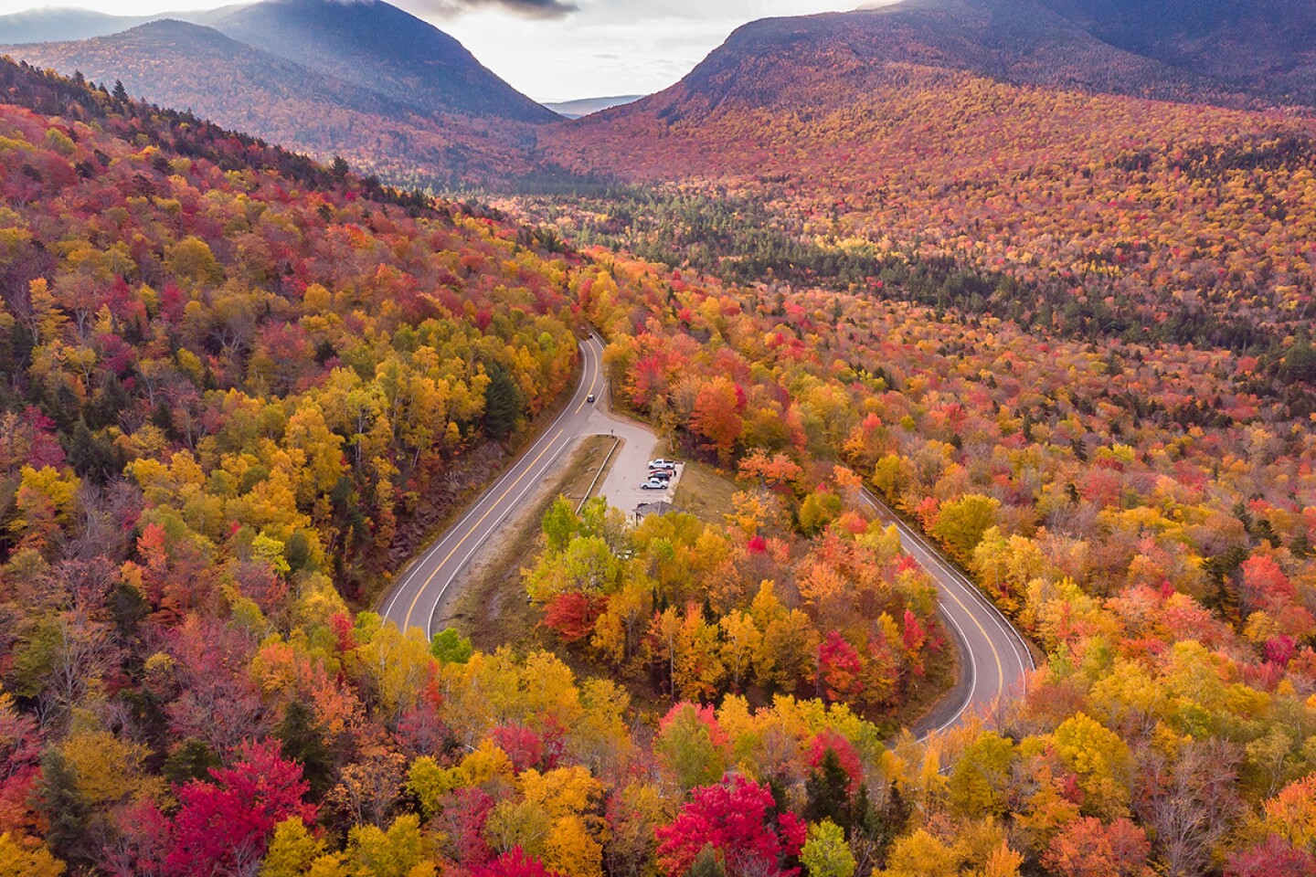 Aerial view of the Kancamagus Highway curving through red, yellow, and green forest