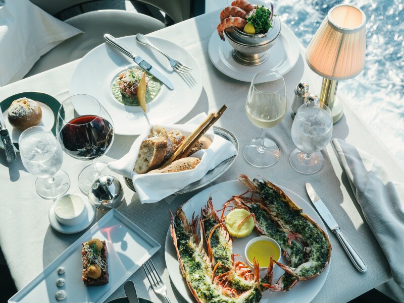 An overhead view of a dining table set for two, with seafood, wine, and bread