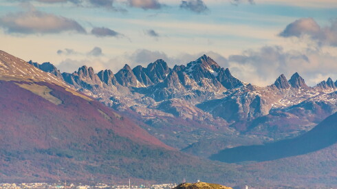 A view of peaked mountains with a small amount of snow in Puerto Williams, Chile, with the Beagle Channel in the foreground
