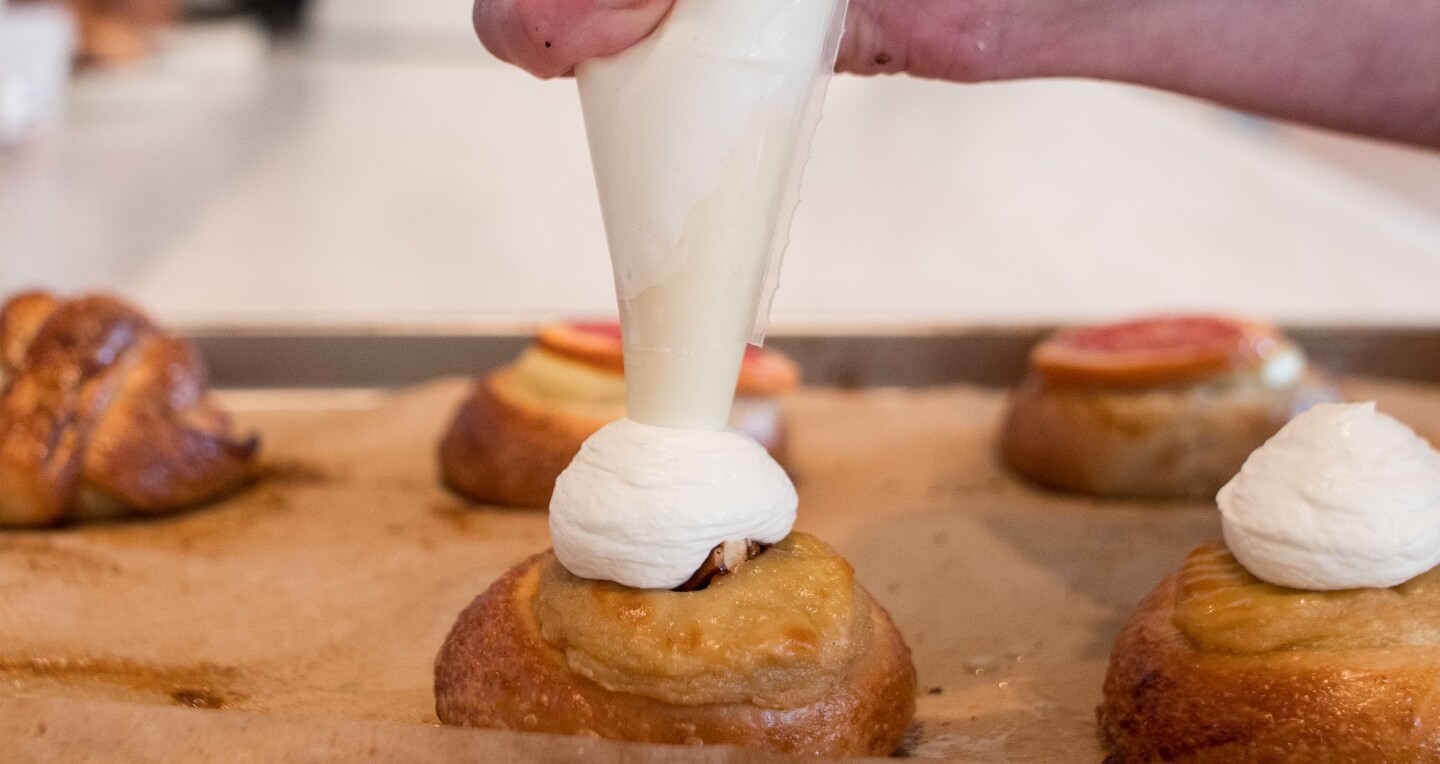A baker piping cream on a tray of pastries at Apotek 57 in Copenhagen, Denmark