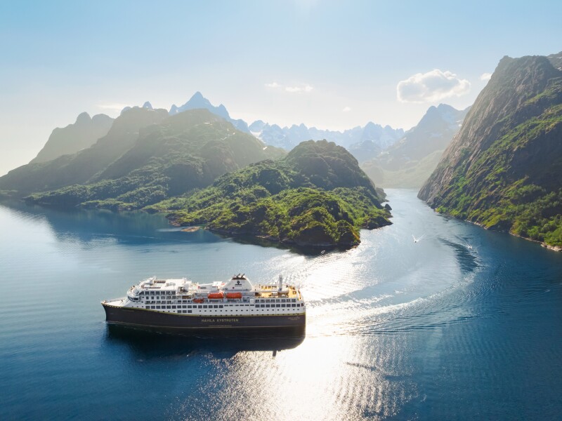 A Havila cruise ship sailing among rugged green islands