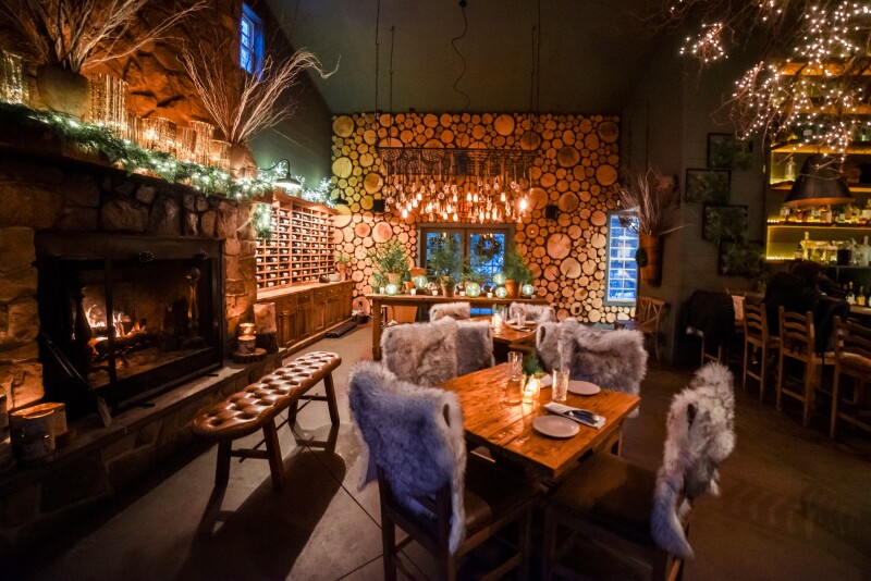 The dining room with a fire place and wood finishings of Earth at Hidden Pond in Maine