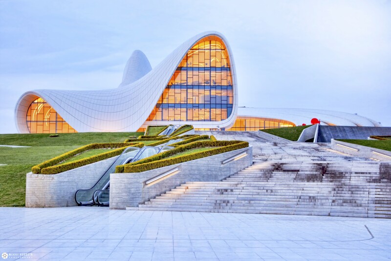 Exterior of curvy, white multi-story building with interior lights on
