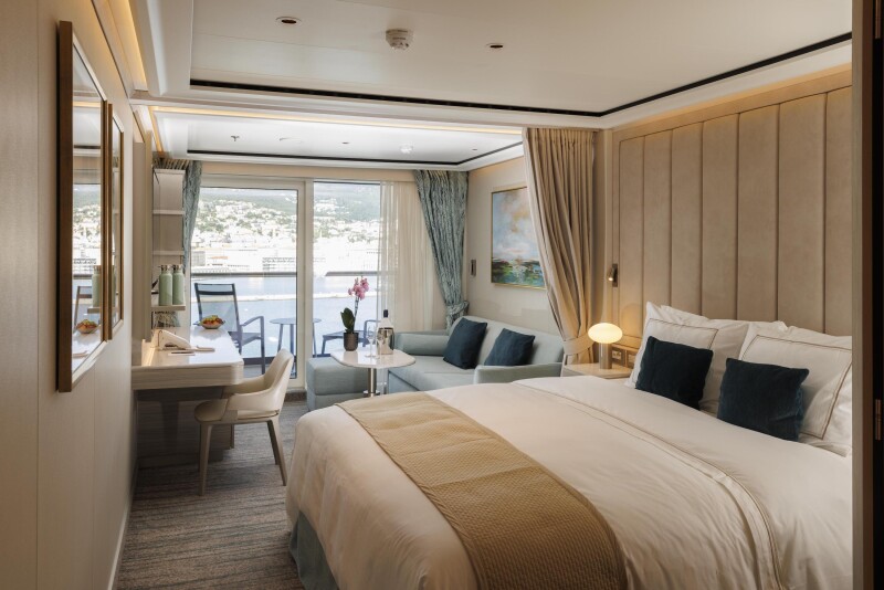 Image of a suite on the Silver Nova with a bed, sitting area, balcony and a bottle of champagne and two glasses on a coffee table