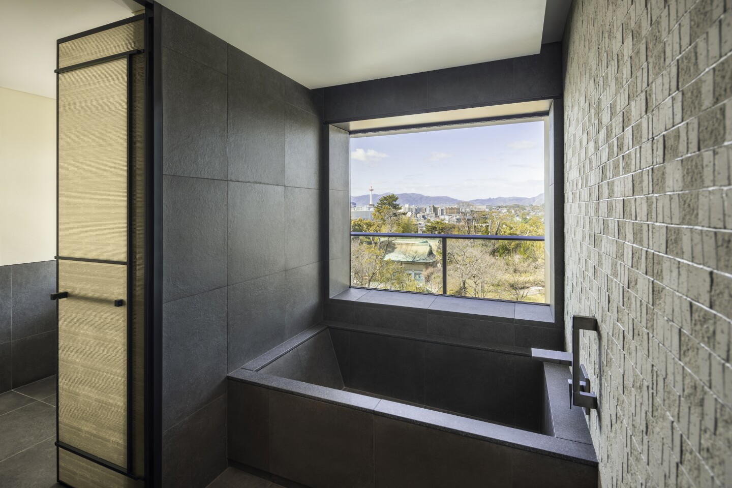 The bathroom of a Deluxe Garden Suite, with large black soaking tub beside a window