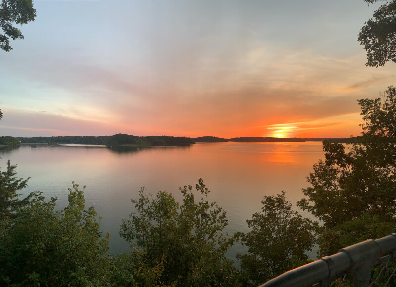 Sun setting over a lake with trees framing view