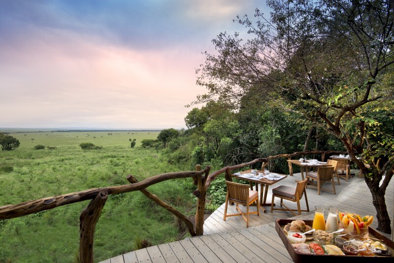 A breakfast spread on a patio at Bateleur Camp in Kenya's Maasai Mara, with views of green fields