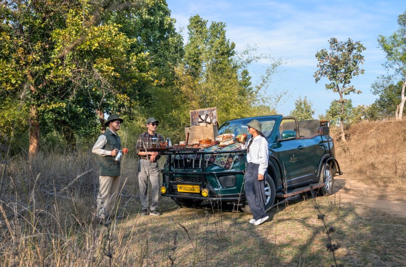 Three people standing next to Jeep, with snacks on hood