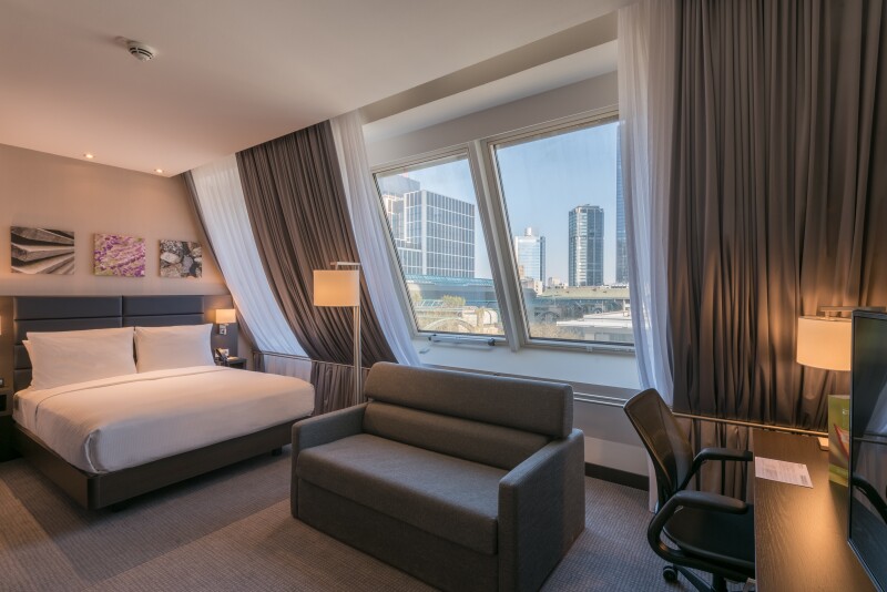 A photograph of a guest room with a view of Frankfurt’s skyline at Hilton Frankfurt City Centre, Germany