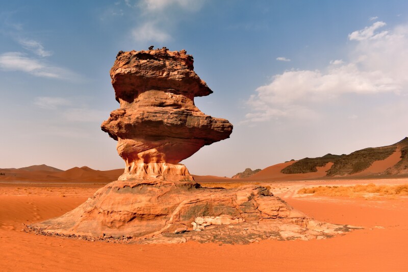 A rock monument known as La Theiere (the Teapot) surrounded by rocky reddish-orange desert