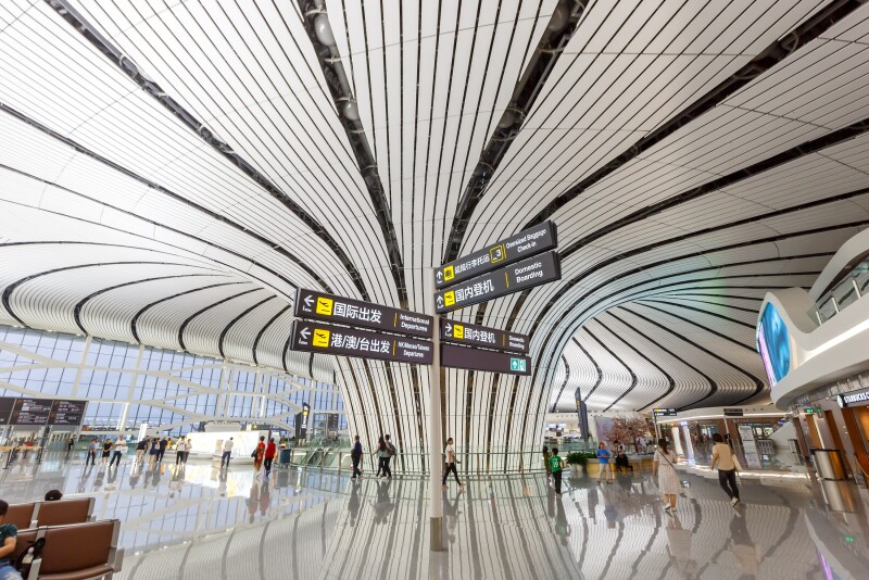 Interior of airport terminal with curvy brown-striped white ceiling reflected on shiny floor