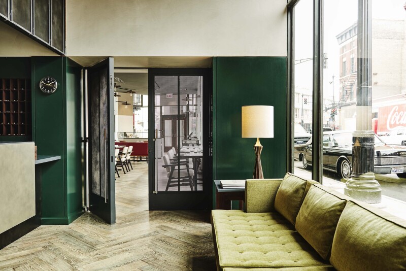 The lobby of the Robey Chicago has a midcentury-modern aesthetic, with long sofa and green accents