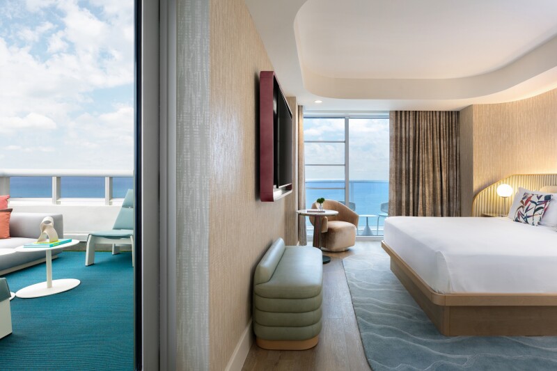 A guest room at Andaz Miami Beach with a king bed with white bedding and a partial view of an oceanview balcony on the left