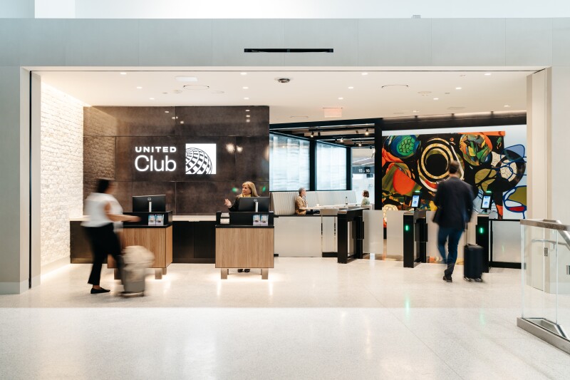 Entrance to United lounge at Newark Airport's Terminal A with a few passengers entering past colorful abstract painting