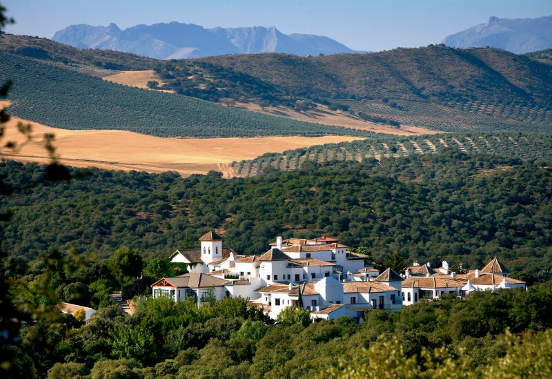 Aerial view of red-roofed white buildings of Finca la Bobadilla, with Sierra de Loja in distance