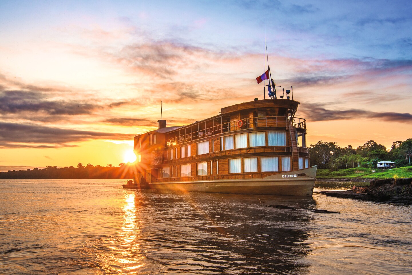 Exterior view of the Delfin II, a small river cruise ship, on Peru's Upper Amazon at sunset