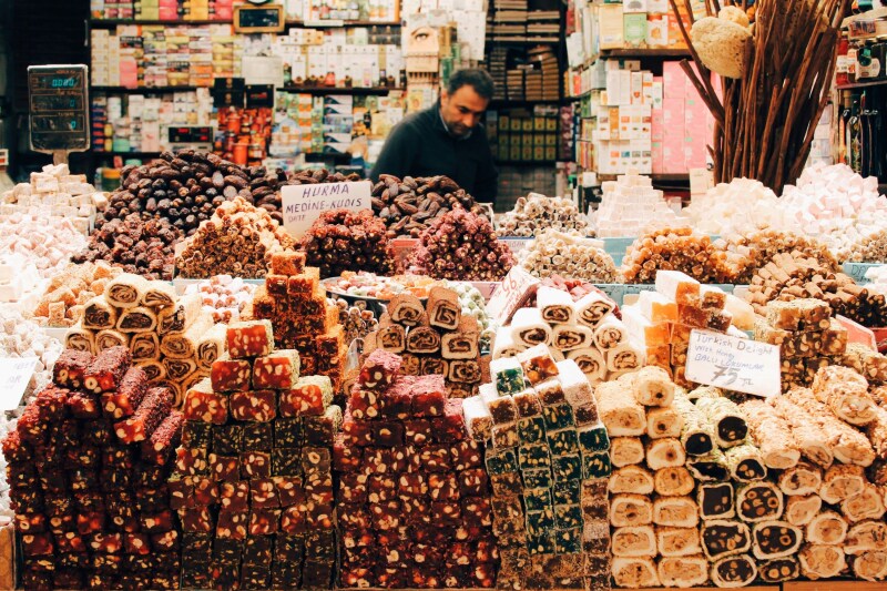 Shop with stacks and stacks of colorful Turkish treats, and a shopkeeper in the background