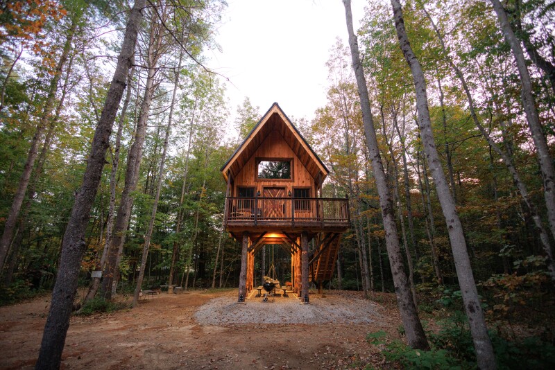 Small wooden cabin on stilts, surrounded by trees