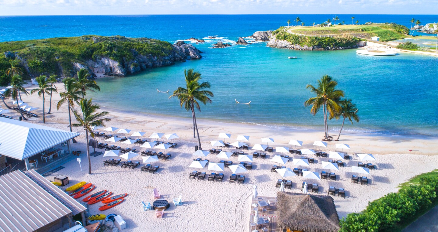 A high view of the beach umbrellas and palm trees overlooking the ocean at the Princess and Beach Club in Bermuda