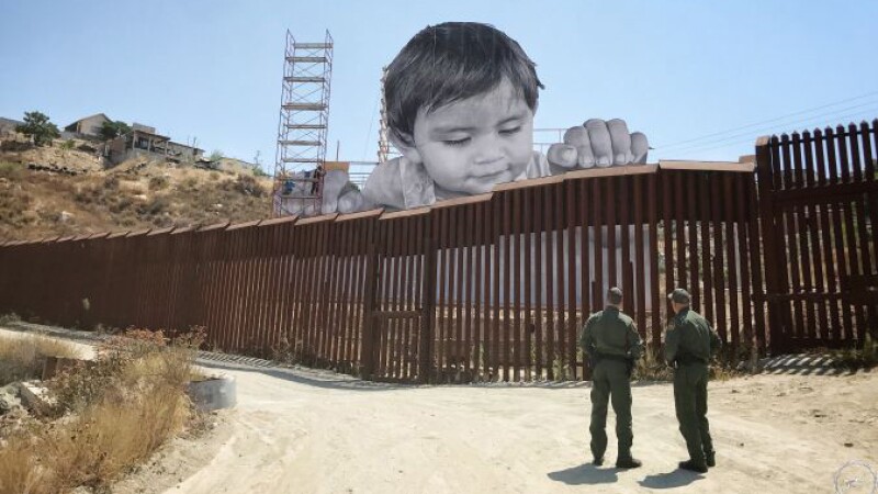 A massive photo of baby Kikito peers over the border fence in Tecate.