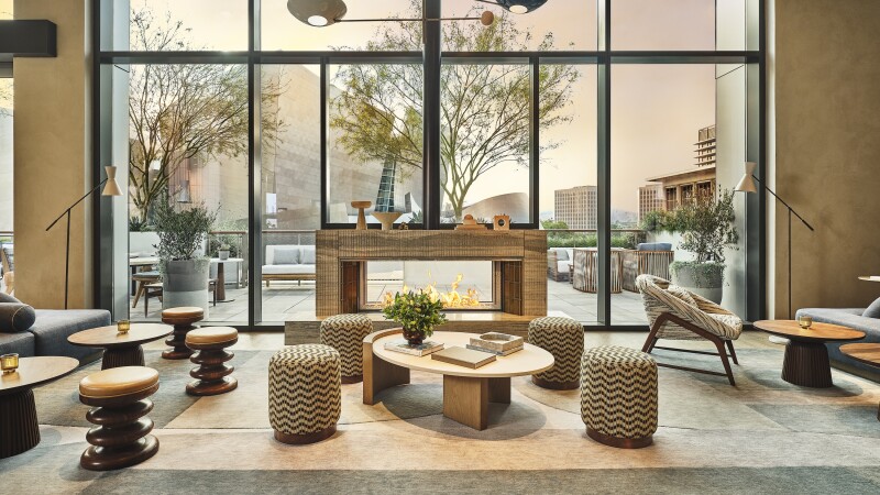Lobby with fireplace, ottomans with zigzag patterns, wood stools, and floor-to-ceiling windows