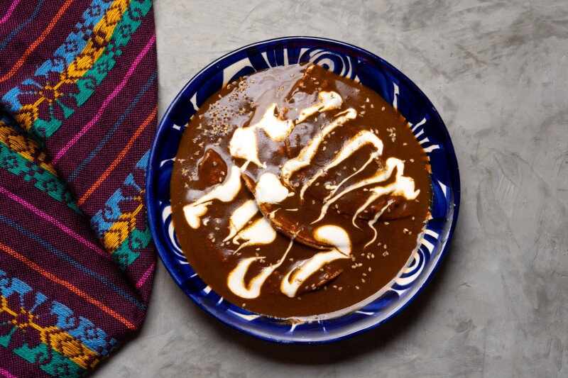 A blue plate of chicken enchiladas with mole sauce