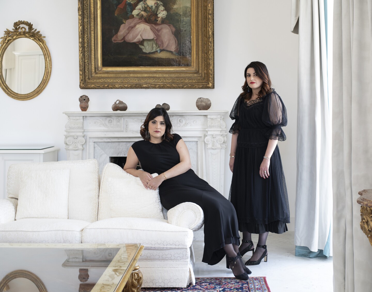 آتیلیا آوینو (چپ) و ماریلا آوینو (راست) با لباسهای مشکی در اتاقی عمدتاً سفید در Palazzo Avino، با مبل و نقاشی تاریخی روی دیوار