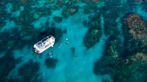 Aerial of boat and snorkelers on the reef