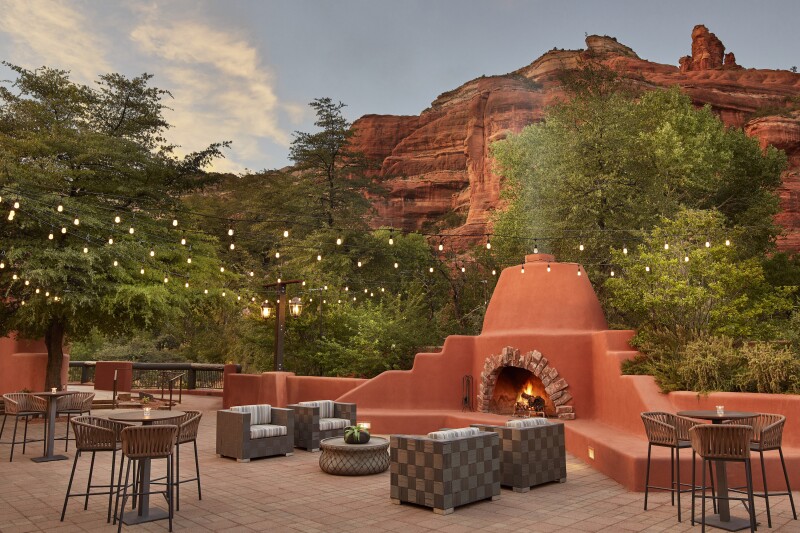 Deck with terra-cotta colored fireplace at Enchantment Resort in Sedona, with red rocks in background