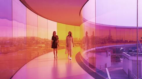 A couple walk through a purple and orange glass walkway
