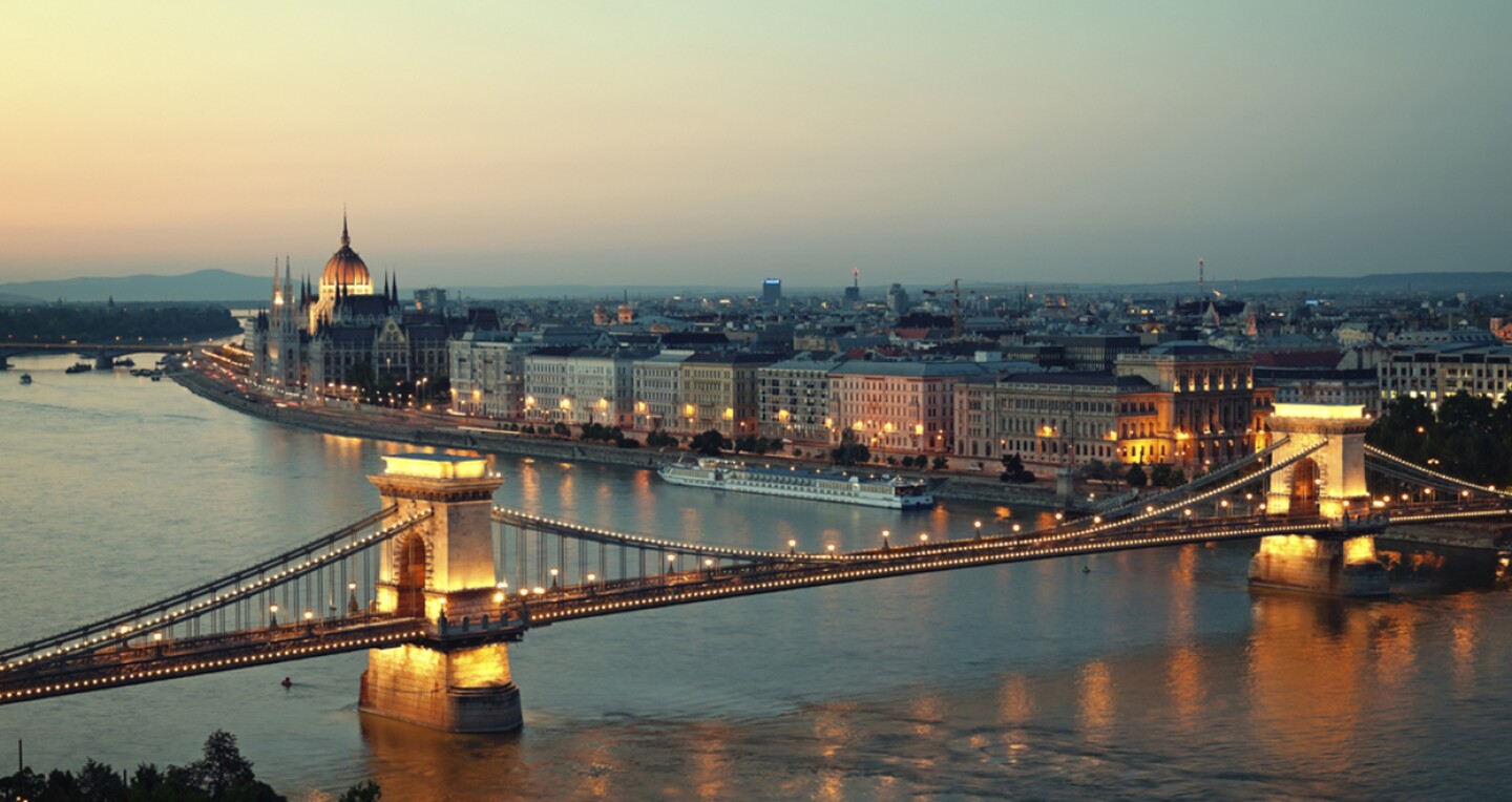 An aerial view of the Hungarian Parliament over a bridge at sunset.