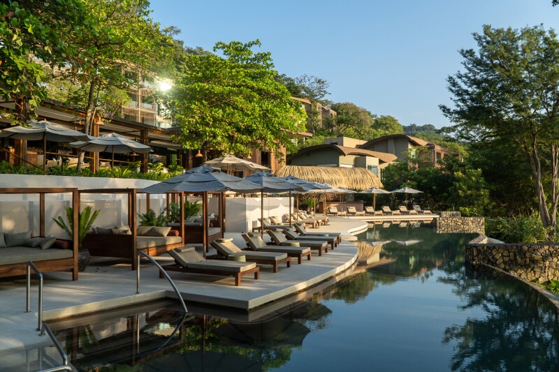 The adults-only pool at Andaz Costa Rica at Peninsula Papagayo, lined with empty beige lounge chairs and sun umbrellas