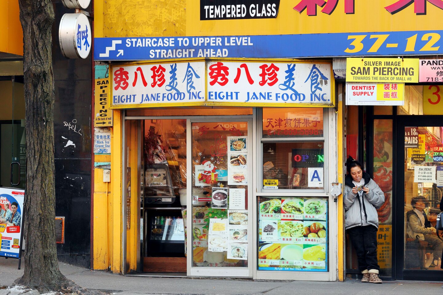 Yellow storefront of Eight Jane Food, with glass plastered with menus