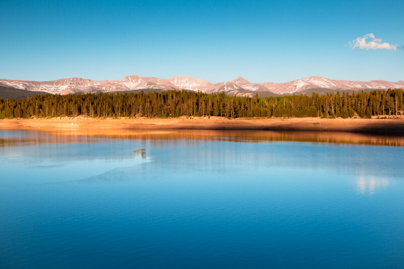 Flat water of Turquoise Lake near Leadville, in foreground, with forest and mountains in distance
