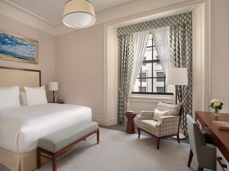 Interior of the Westminster Suite at the Raffles London at the OWO, with large window and a muted palette accented in green