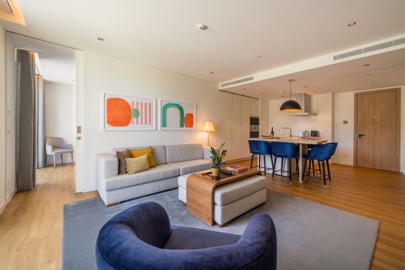Interior of a Martinhal Lisbon Oriente's accommodation, with wooden floors, blue chairs, and brightly colored art on white walls