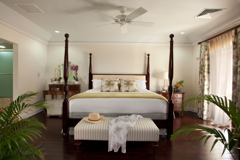 A Grand Luxury Oceanfront Suite at BodyHoliday on St. Lucia, with four-poster bed, wood floors, ceiling fan, and white walls