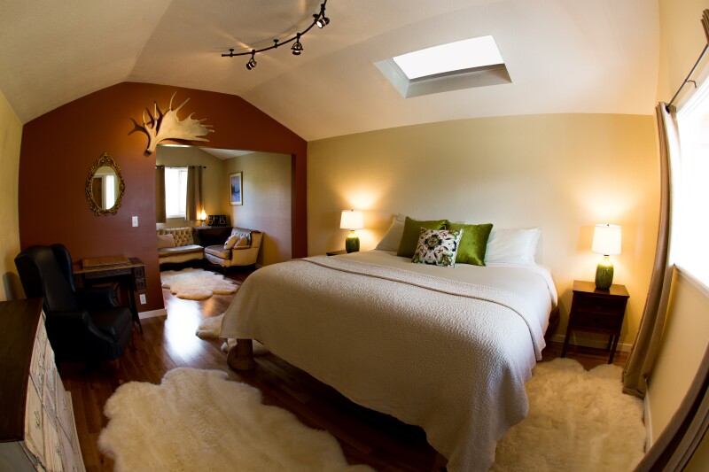 This guest room at Ultima Thule Lodge has wooden floors covered by plush white carpets, and an antler hangs on the wall.