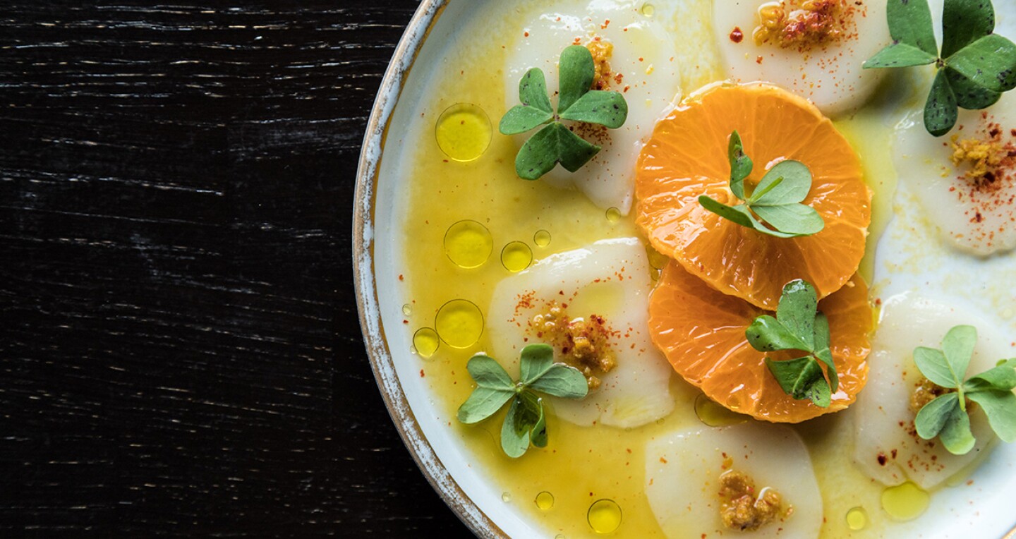 A bowl of soup topped with orange slices