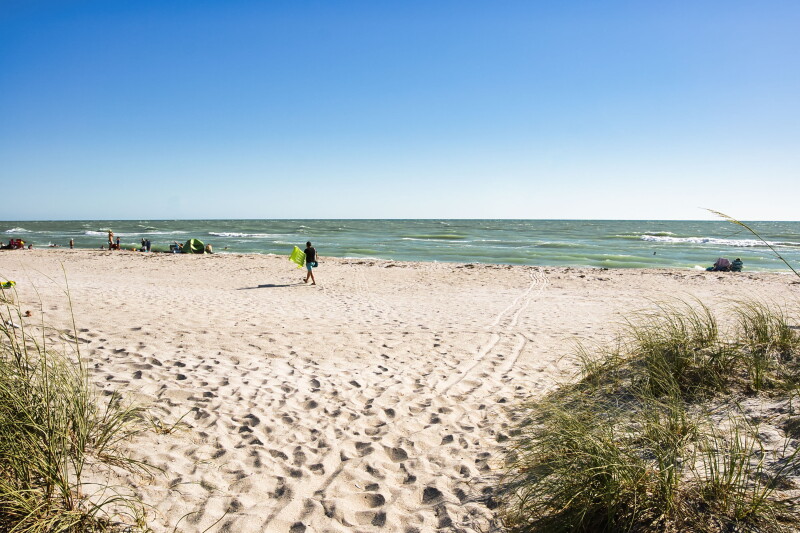 Wide, flat beach full of footprints, with a few people