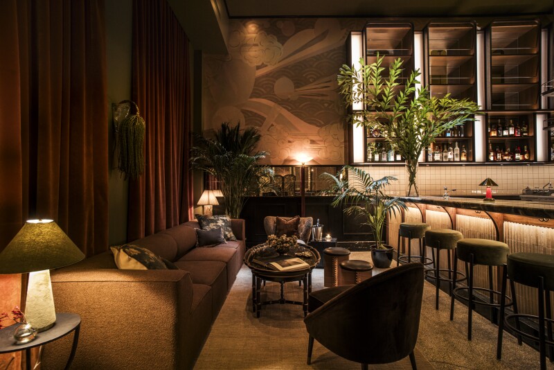 The Tusk Bar has moody, low lighting and plenty of couch seating, with dark red curtains hanging against one wall