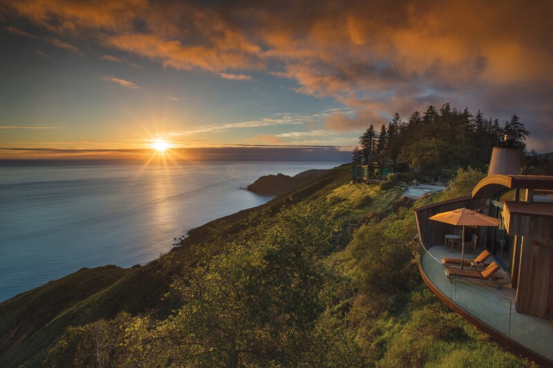 Post Ranch Inn in Big Sur, California, sits atop a coastal ridge with the sun setting behind the ocean.